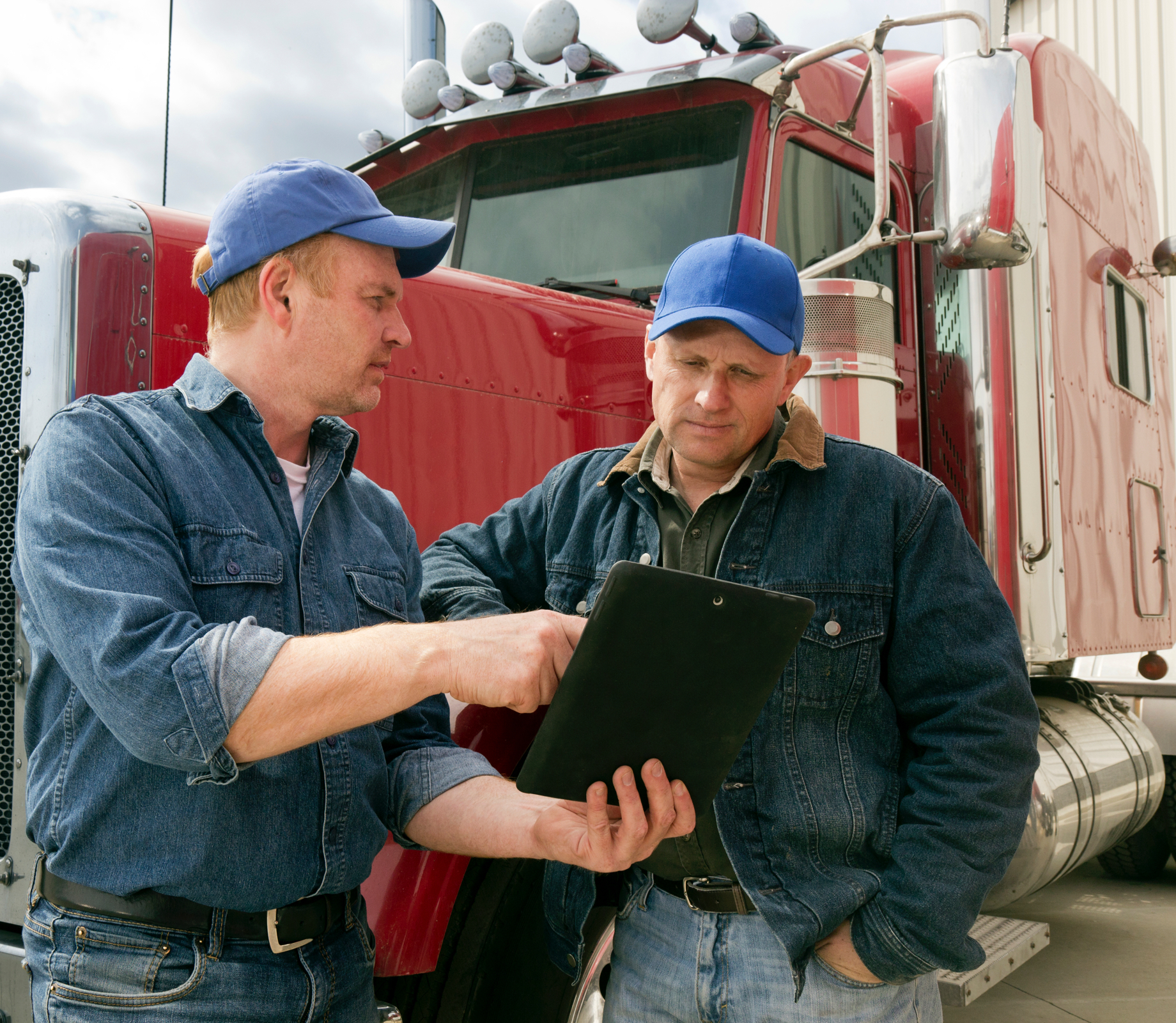 Deux chauffeurs qui regardent un note pad devant un camion poid lourd